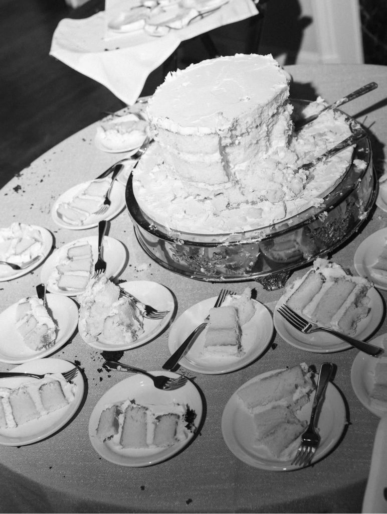 A wedding cake that has been cut into many pieces on a serving table for guests. Custom Wedding Cakes @ Custom Cake Studio. Columbus, Georgia.